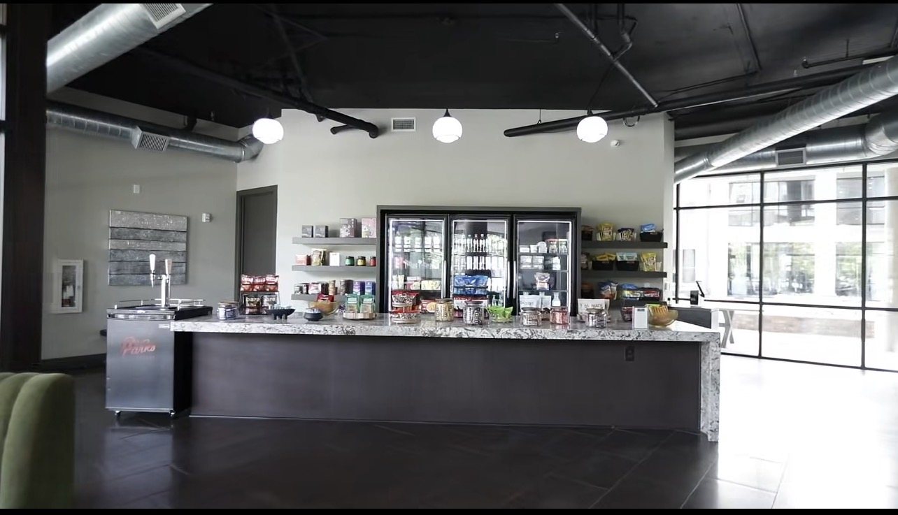 Micro mart build-out with coolers, shelving, and a stone counter in an apartment amenity space